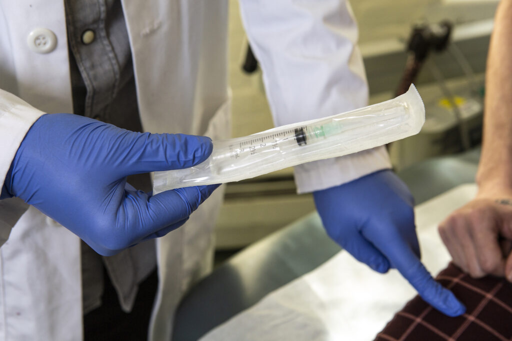 a_doctor_showing_a_patient_a_syringe_used_to_inject_testosterone_and_pointing
