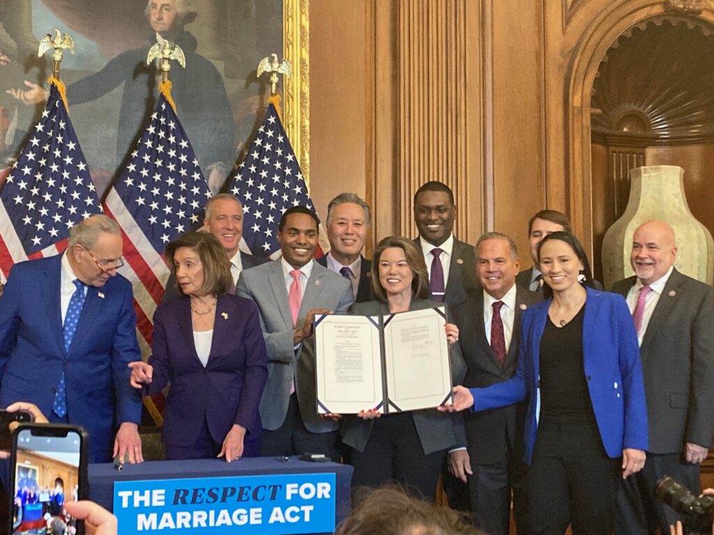 United States senators and representatives hold up signed "Respect for Marriage Act"