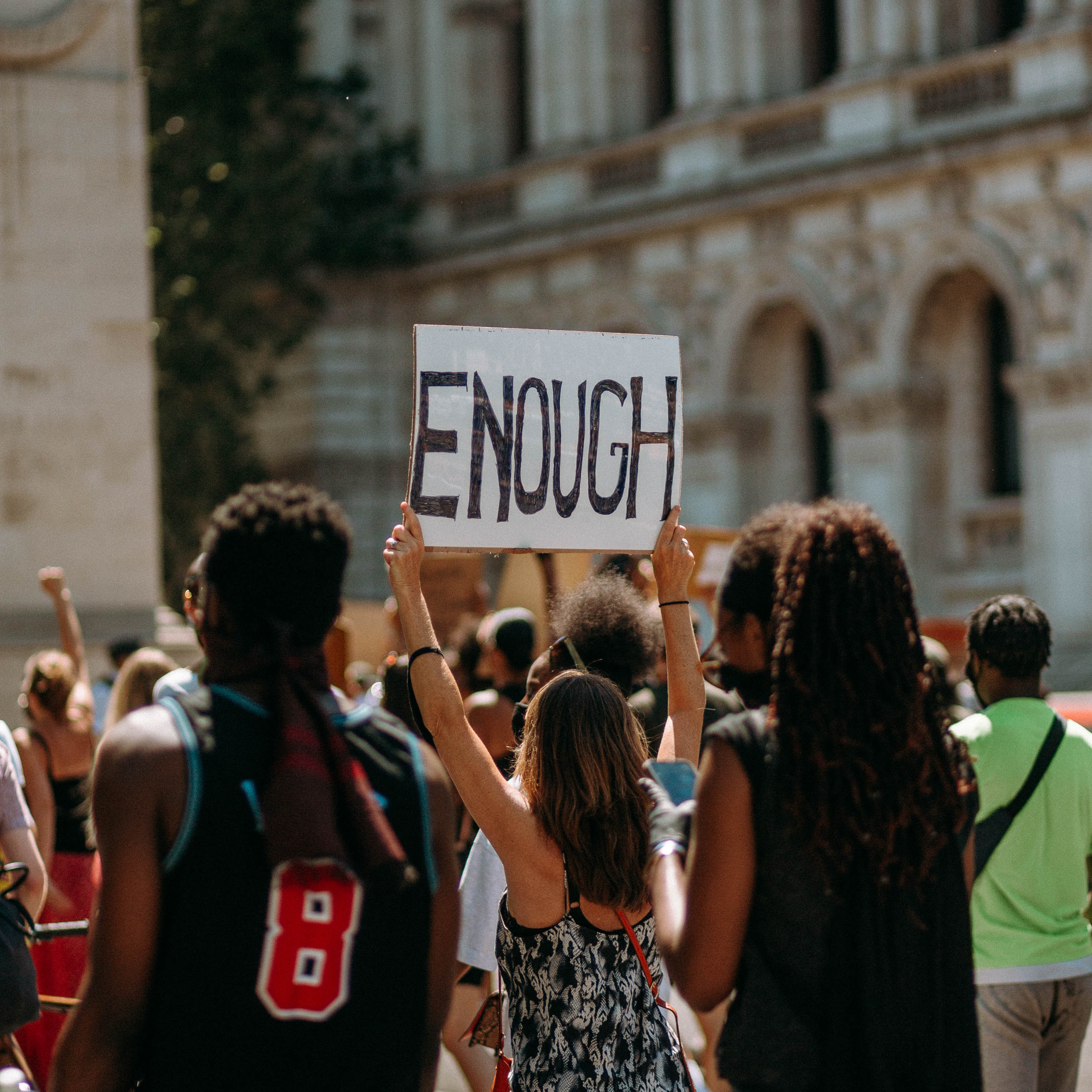 Protester holds up a sign that reads "Enough" amongst crowd.