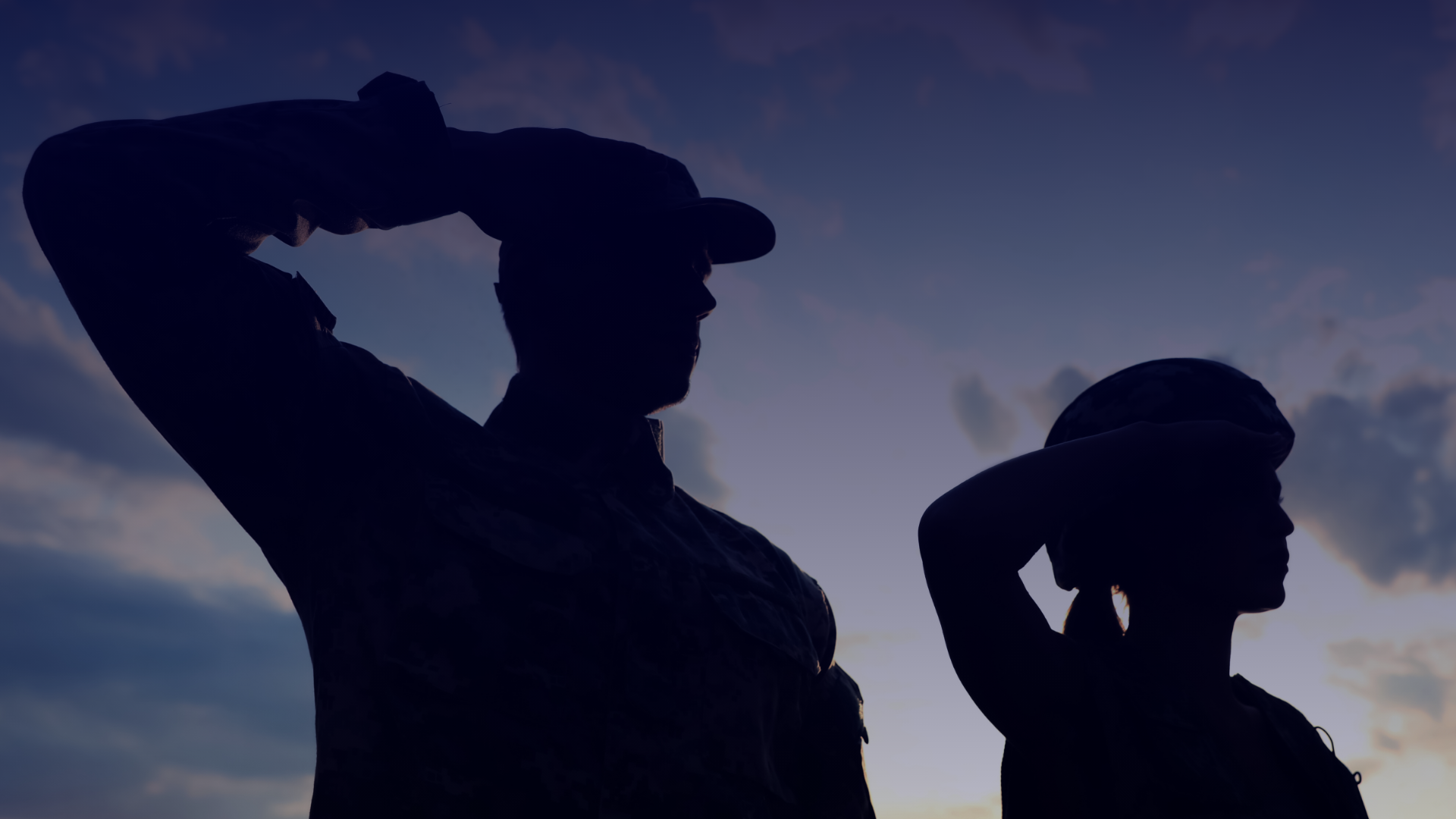 two silhouetted military service members saluting