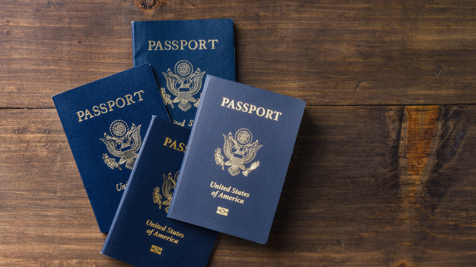 four United States passports laying on a wooden surface