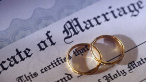 two gold rings laid on top of a marriage certificate