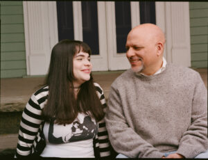 trans child sophie and father josh sitting outside and smiling at each other