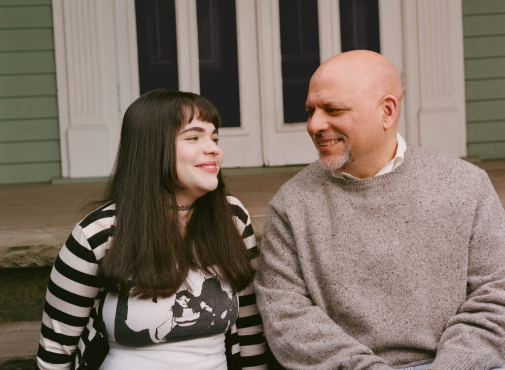 trans child sophie and father josh sitting outside and smiling at each other