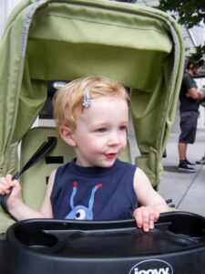 baby with clips in hair in a green stroller