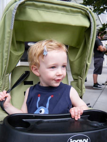 baby with clips in hair in a green stroller